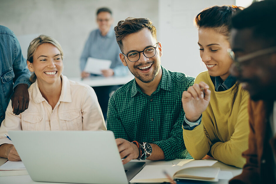 Study Talk Ein glücklicher College-Student und seine Freunde benutzen einen Laptop und lernen gemeinsam im Klassenzimmer.